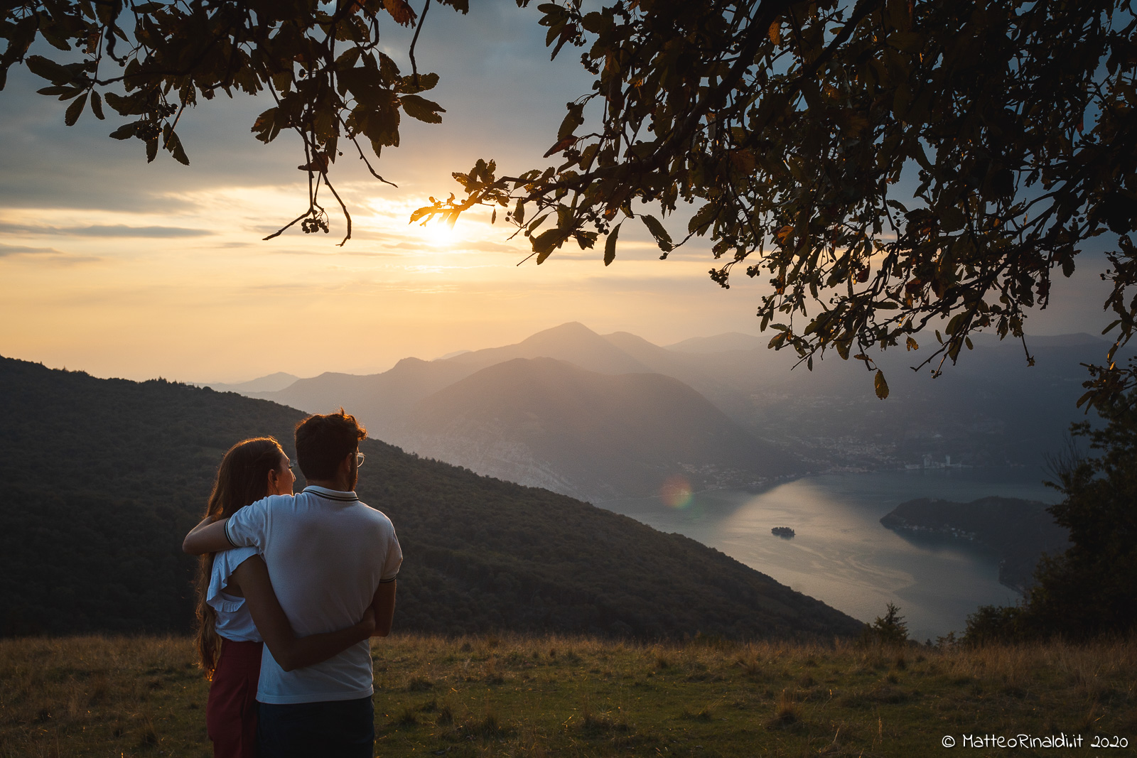 Coppia di futuri sposi che passeggia in mezzo alla natura, al tramonto, sulle creste delle montagne Bresciane attorno al lago d'Iseo